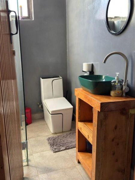 Baño moderno con lavabo verde y mueble de madera en Piye Boutique Hotel
