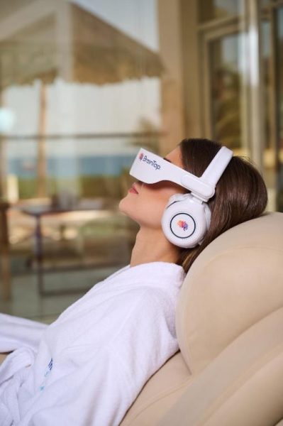 Mujer relajada con auriculares BrainTap durante sesión de bienestar en TheLifeCo Sharm El Sheikh