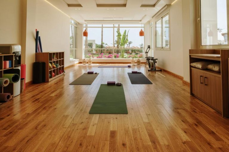 Sala de yoga con esterillas y suelo de madera en TheLifeCo Sharm El Sheikh con vistas al jardín