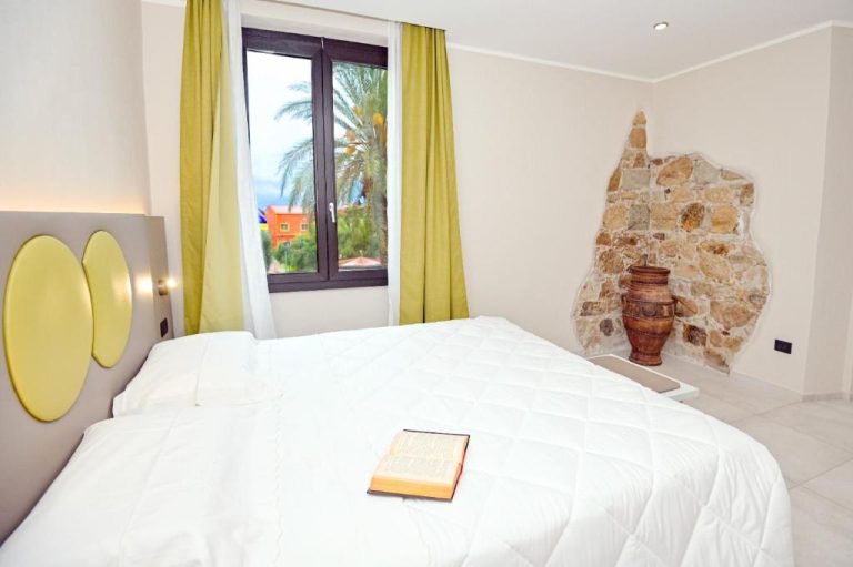 Habitación doble con pared de piedra y jarrón decorativo en Hotel Corallo New