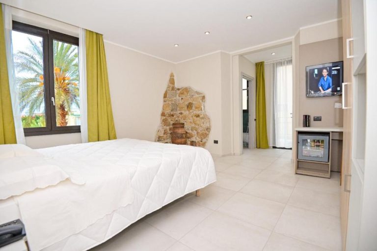 Habitación doble con chimenea de piedra y televisión del Hotel Corallo New con vistas a palmeras