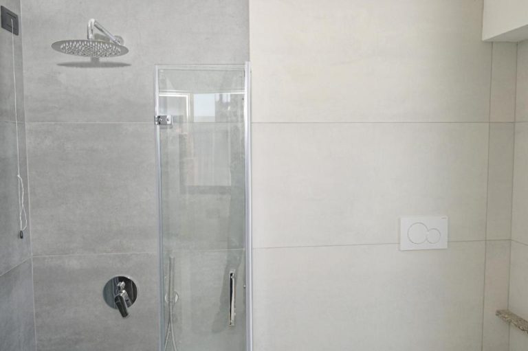 Ducha de lluvia con cabina de cristal y grifería cromada en el baño del Hotel Corallo New