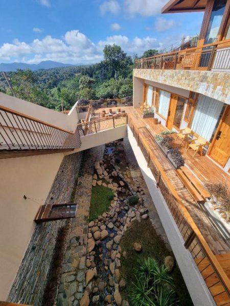 Terraza con arroyo de piedras y vistas a la montaña en MăngDiang Boutique Hotel rodeado de naturaleza