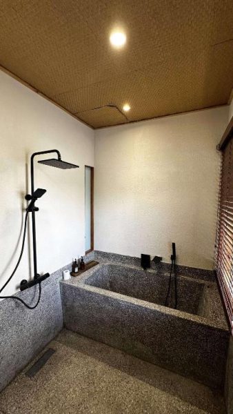 Baño de piedra natural con bañera empotrada y ducha negra en MăngDiang Boutique Hotel
