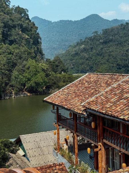 Terraza de madera con vistas al lago y montañas boscosas en Ba Be Jungle Houses, Vietnam