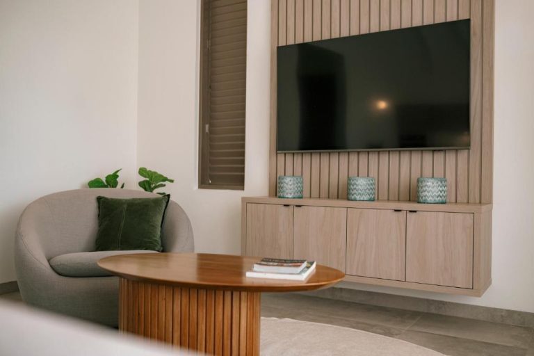 Salón moderno con TV empotrada y mueble de madera en The Jazmyn Blue Bay Curaçao Resort