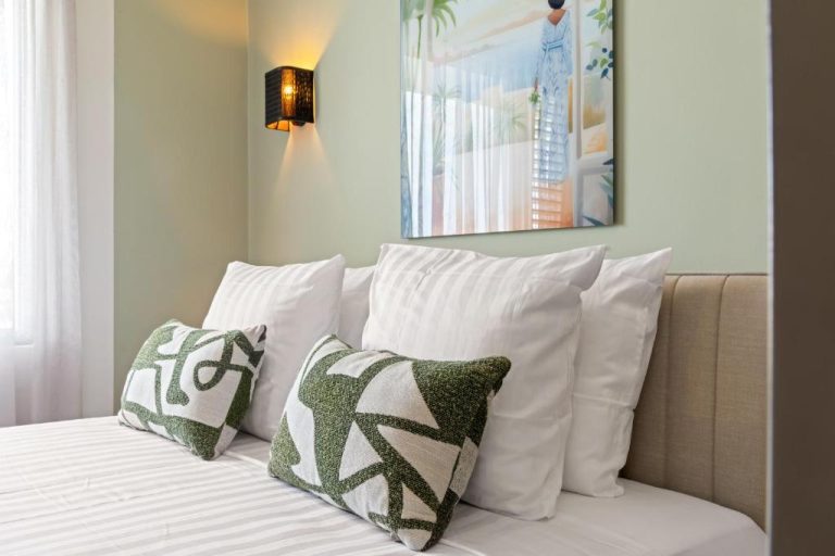 Habitación doble de The Ivy Blue Bay Curaçao con cama blanca, almohadas verdes y decoración tropical