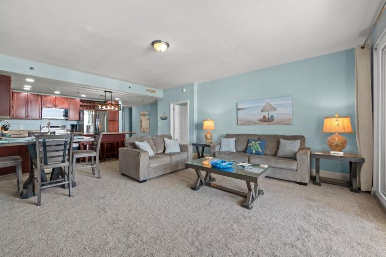Salón con sofás y cocina abierta de estilo playero en el resort Laketown Wharf, Panama City Beach