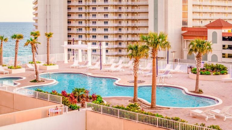 Piscina exterior con palmeras y tumbonas del Laketown Wharf Resort con vistas al mar en Panama City Beach