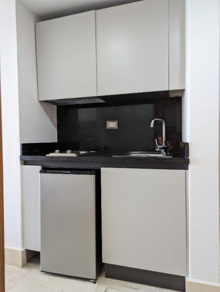 Cocina equipada con encimera negra, fregadero, vitrocerámica y minibar en Hacienda Samana Bay Hotel