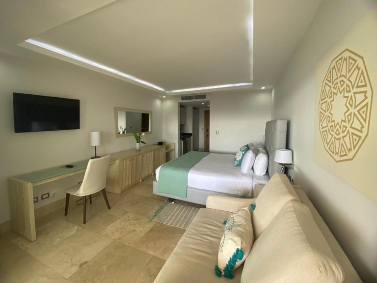 Suite moderna con cama doble, sofá y decoración en tonos turquesa del Hacienda Samana Bay Hotel