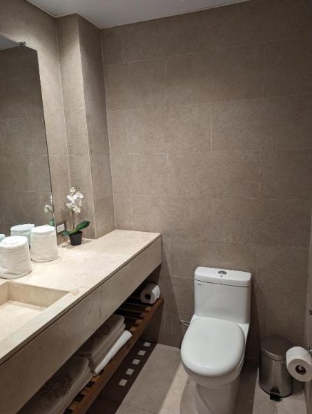 Baño moderno con lavabo de mármol, inodoro y toallas en Hacienda Samana Bay Hotel