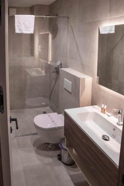 Baño moderno con ducha de cristal, inodoro suspendido y lavabo en el Hotel Onogošt