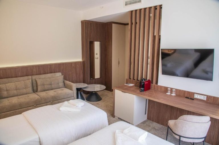 Habitación doble moderna con sofá, TV y cafetera en Hotel Onogošt, decoración en madera