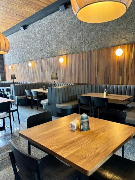 Restaurante interior del Iconik Hotel con cabinas tapizadas en gris y mesas de madera iluminadas
