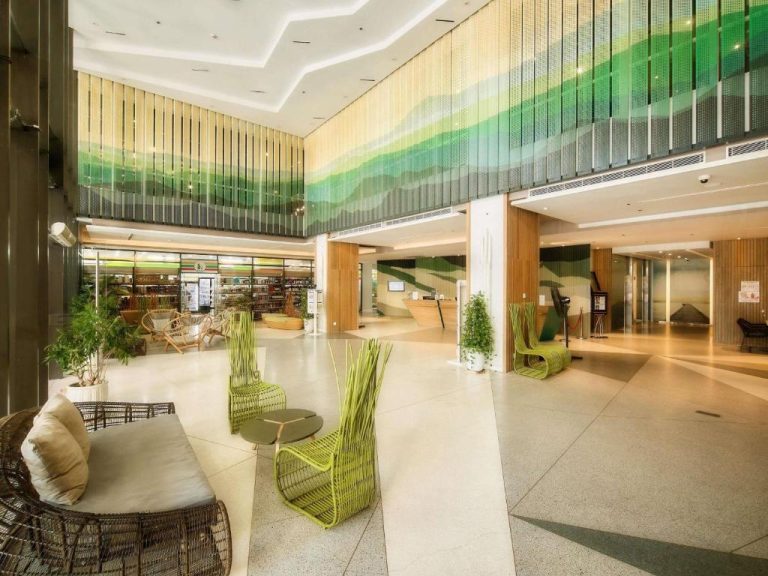 Lobby moderno con sillas verdes y decoración tropical del ibis Styles Nha Trang
