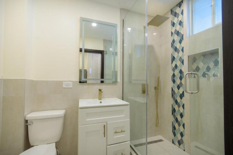 Baño moderno con ducha de cristal y azulejos decorativos en apartamento Sandcastles 1 Bedroom 14