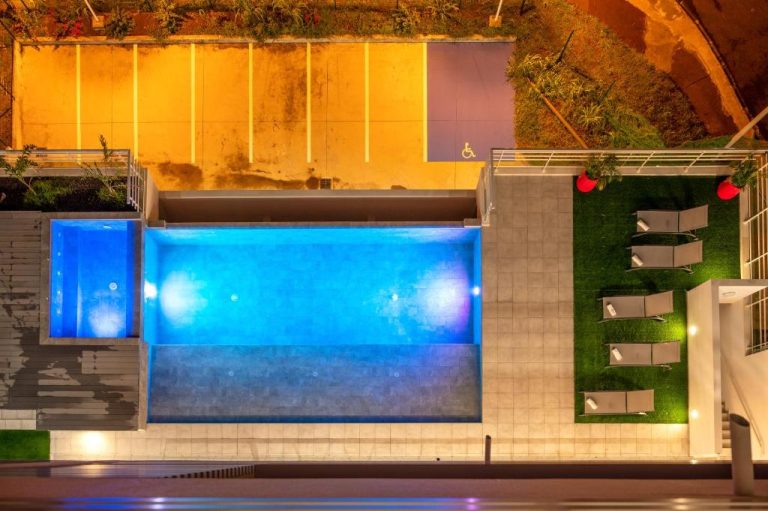 Vista aérea nocturna de la piscina iluminada y zona de tumbonas del B&B HOME Fort-de-France Marina