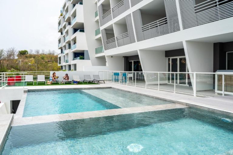 Piscina exterior con tumbonas del B&B Home Fort-de-France Marina junto al edificio de apartamentos
