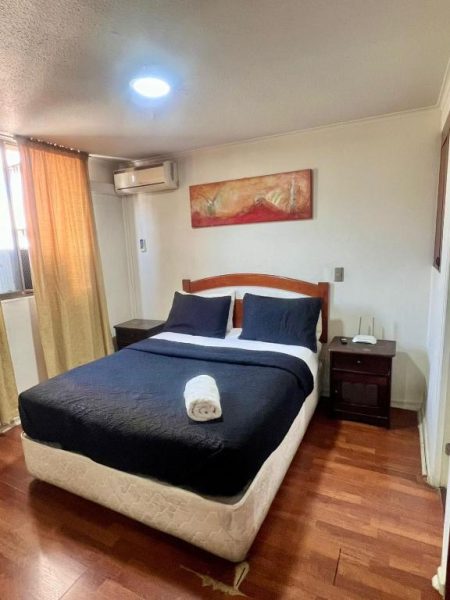 Habitación doble con cama matrimonial y suelo de parqué en Dptos Merced Santiago