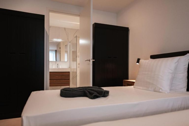 Habitación doble con cama blanca y baño en suite del hotel The Breeze Blue Bay Curaçao Resort
