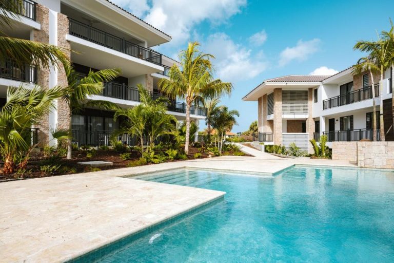 Piscina exterior con palmeras y villas del The Breeze Blue Bay Curaçao Golf & Beach Resort
