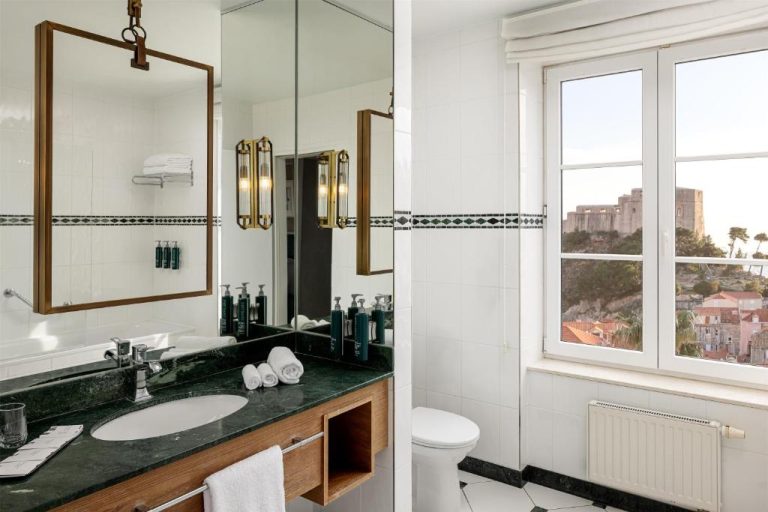 Baño de lujo con encimera de mármol verde y vistas a la fortaleza en Hilton Imperial Dubrovnik