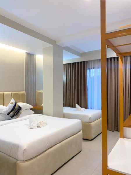 Habitación familiar con dos camas dobles y litera en Olive's Suites, decoración moderna en tonos neutros