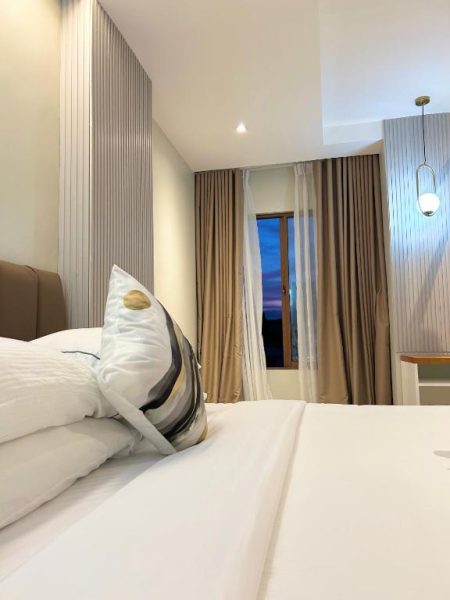 Habitación doble de lujo con cama king size y cortinas doradas en Olive's Suites
