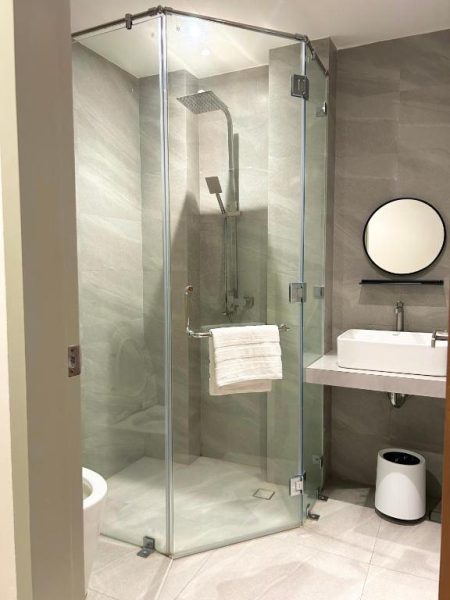 Baño moderno con ducha de cristal y cabezal de lluvia en Olive's Suites