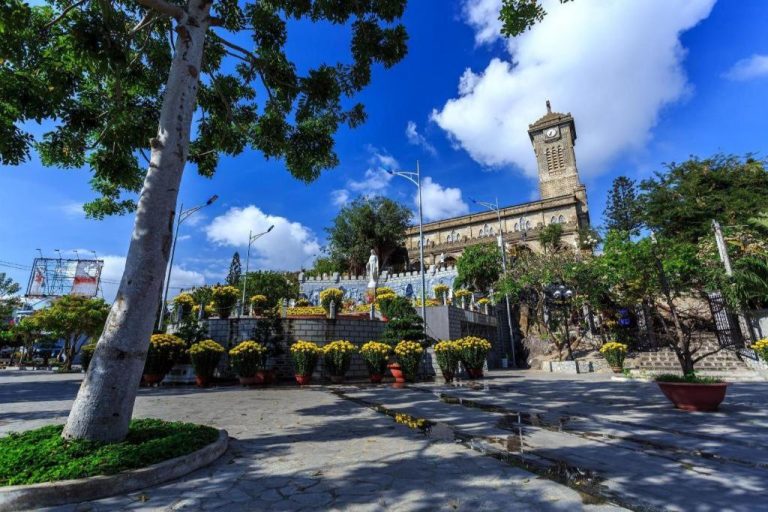 Vista exterior de la catedral de Nha Trang con jardines y flores amarillas cerca del Zen Hotel Nha Trang