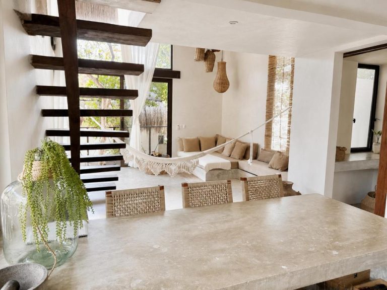 Sala de estar con hamaca y comedor de piedra natural en Ikal Bungalows Tulum con decoración boho