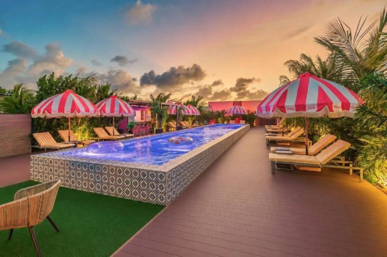 Piscina elevada con azulejos y tumbonas bajo sombrillas de rayas en Privada Stays Boutique Hotel al atardecer