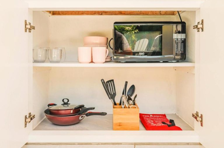 Armario de cocina equipada con microondas, tazas, sartenes y utensilios en Privada Stays Boutique Hotel