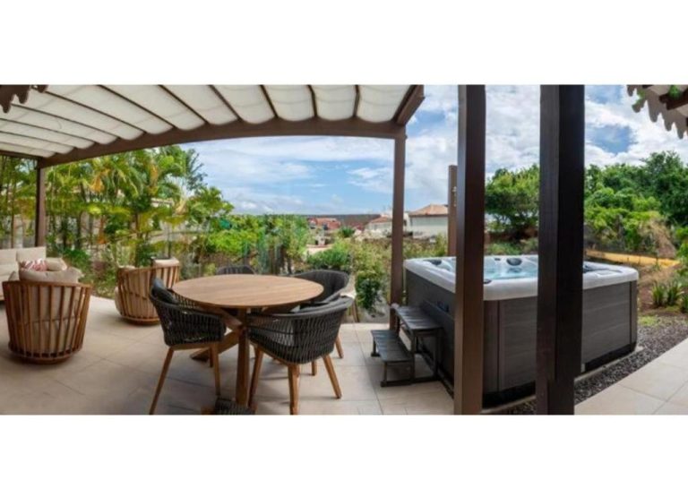 Terraza exterior con jacuzzi, mesa de comedor y vistas al jardín en La Suite Villa