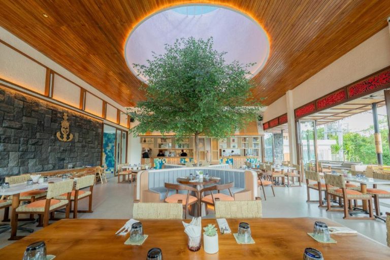 Restaurante interior del Lomo Boutique Hotel Uluwatu con árbol central bajo techo de madera y luz natural