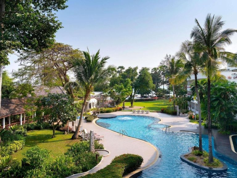 Piscina exterior rodeada de palmeras y jardines tropicales en Novotel Rayong Rim Pae Resort