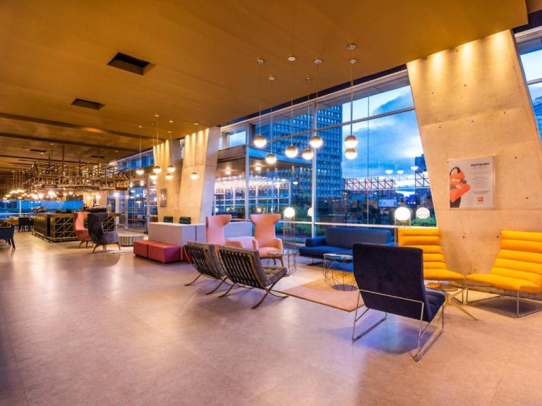 Lobby moderno del ibis Bogota Museo con sillones coloridos y amplia vista panorámica de la ciudad al atardecer
