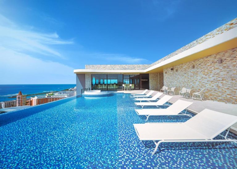Piscina infinity rooftop con tumbonas y vistas al mar en RIHGA Royal Resort Okinawa Chatan