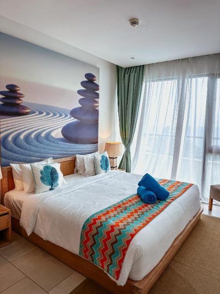 Suite con cama king size y decoración zen en AQUA Boutique Hotel, vistas al océano y detalles en turquesa