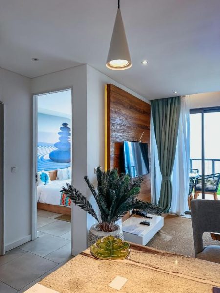 Suite con salón moderno, televisor y acceso al dormitorio en AQUA Boutique Hotel con vistas al océano