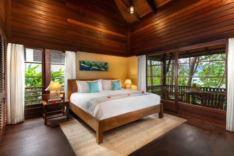 Habitación con cama doble y techo de madera tropical en Enchanted Island Resort con vistas al jardín