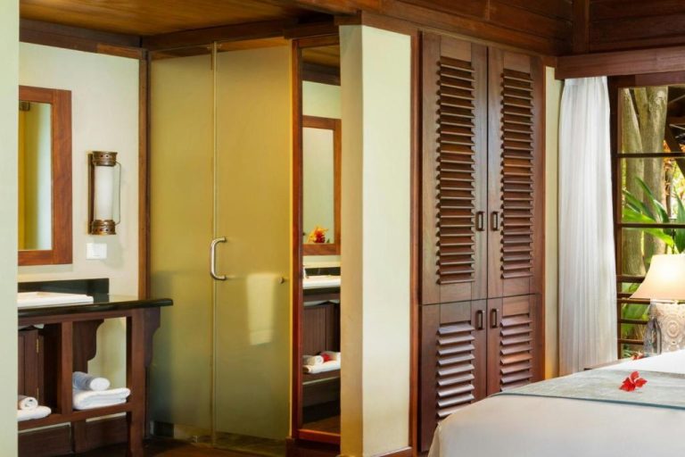 Habitación con armario de madera, baño con ducha de cristal y cama doble en Enchanted Island Resort