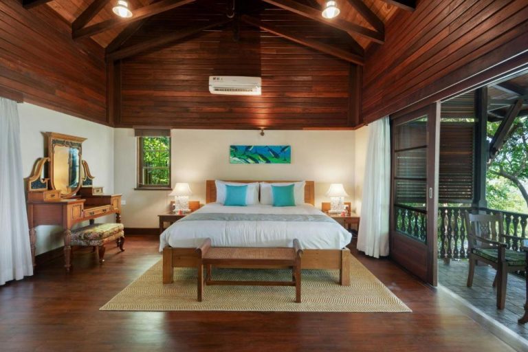 Habitación de lujo con techo de madera y cama doble en Enchanted Island Resort con balcón tropical