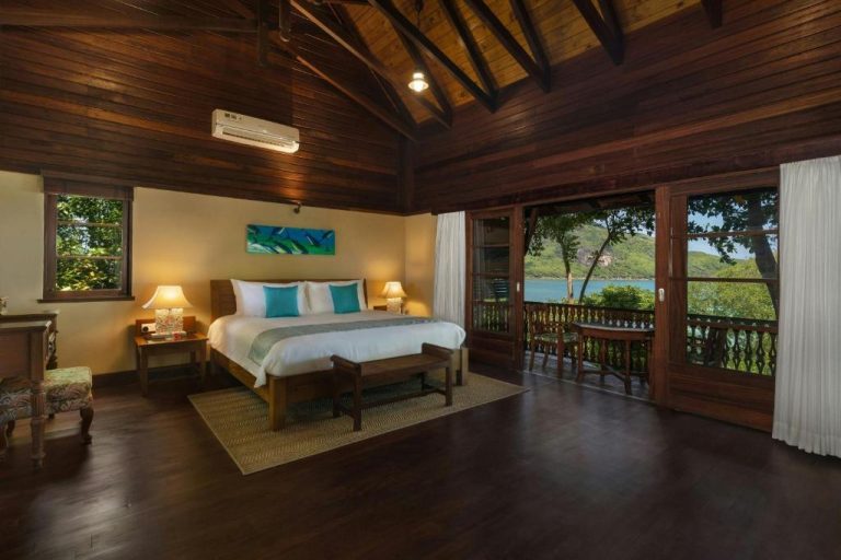 Habitación deluxe con cama doble, techo de madera y balcón con vista al mar en Enchanted Island Resort