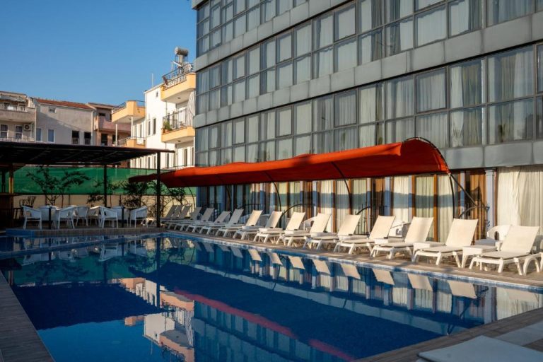 Piscina exterior con tumbonas blancas y toldo rojo del Velaris Boutique Hotel