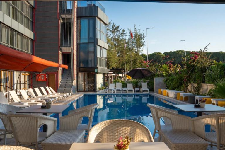 Piscina exterior con tumbonas y zona de relax en el Velaris Boutique Hotel rodeada de jardines