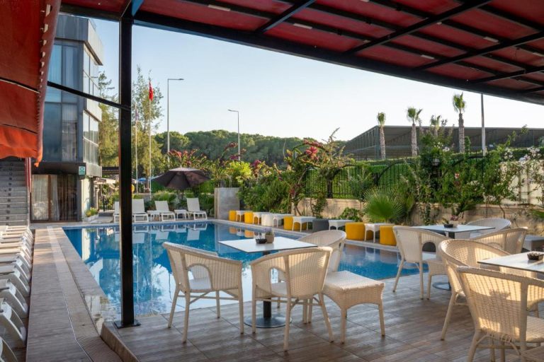Terraza con mesas y sillas junto a la piscina exterior del Velaris Boutique Hotel rodeada de vegetación