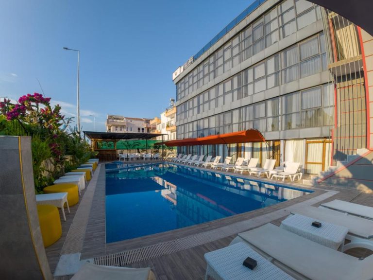 Piscina exterior con tumbonas y sombrillas del Velaris Boutique Hotel en un día soleado