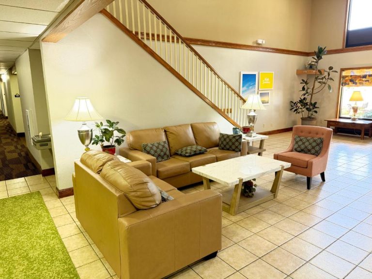 Sala de estar con sofás de cuero y escalera en el lobby del Days Inn & Suites by Wyndham Cuba
